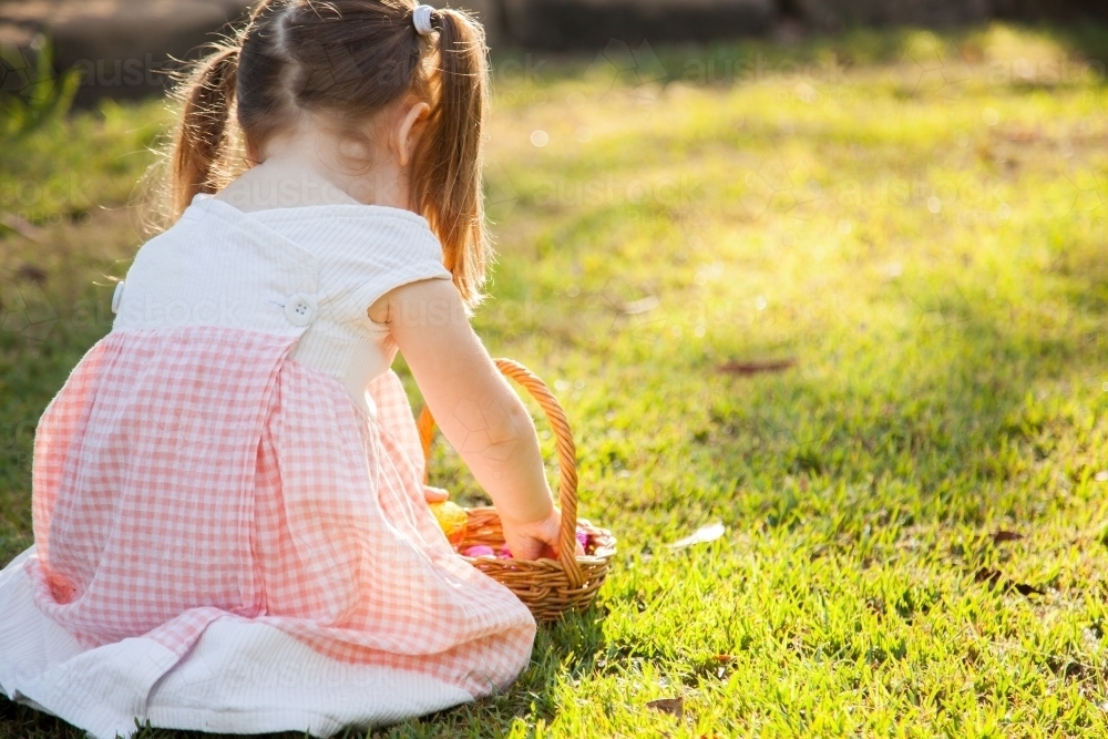 Three year old child on an Easter egg hunt in the garden - Australian Stock Image