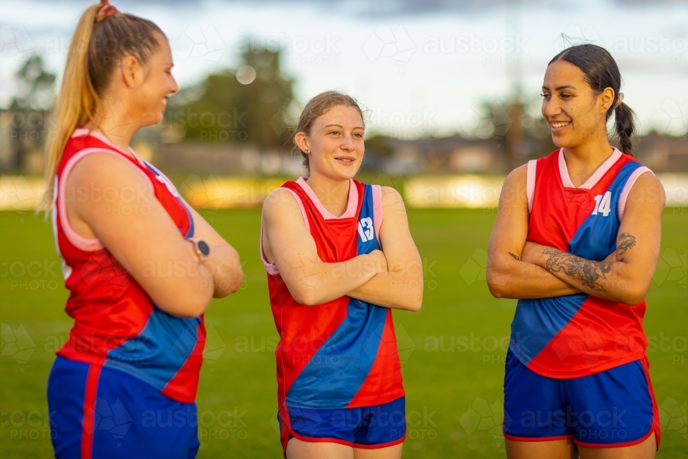 three young women on football field with their arms crossed - Australian Stock Image