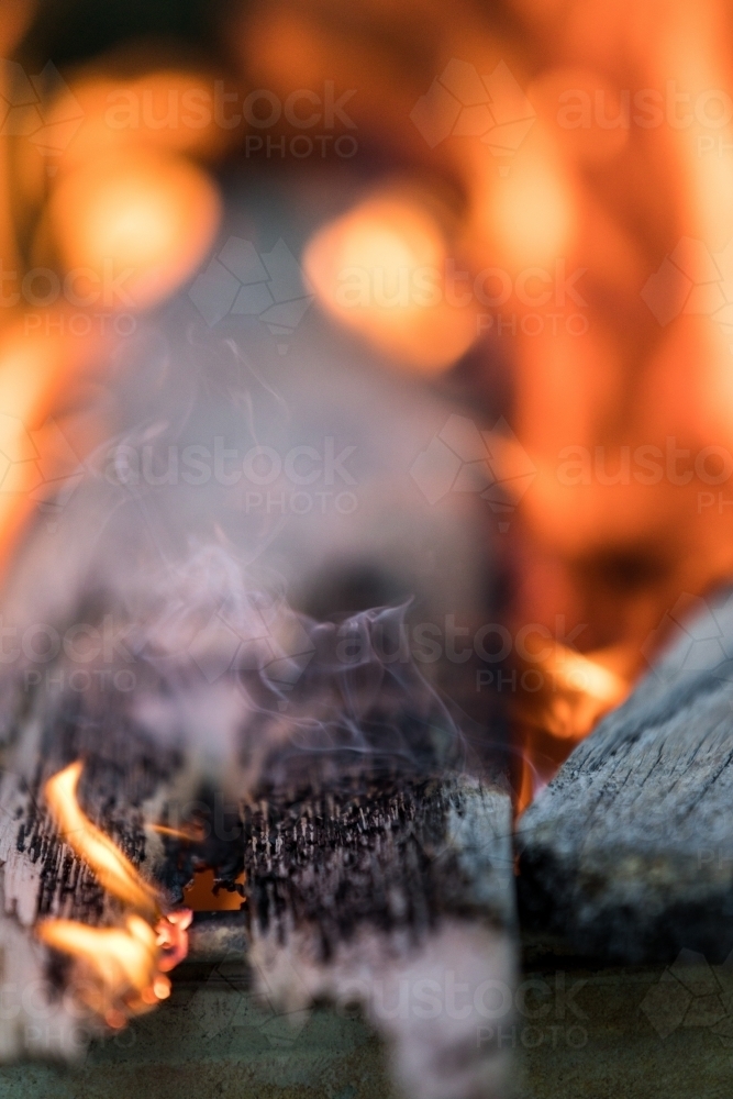 Timber plank smoldering with smoke and fire - Australian Stock Image