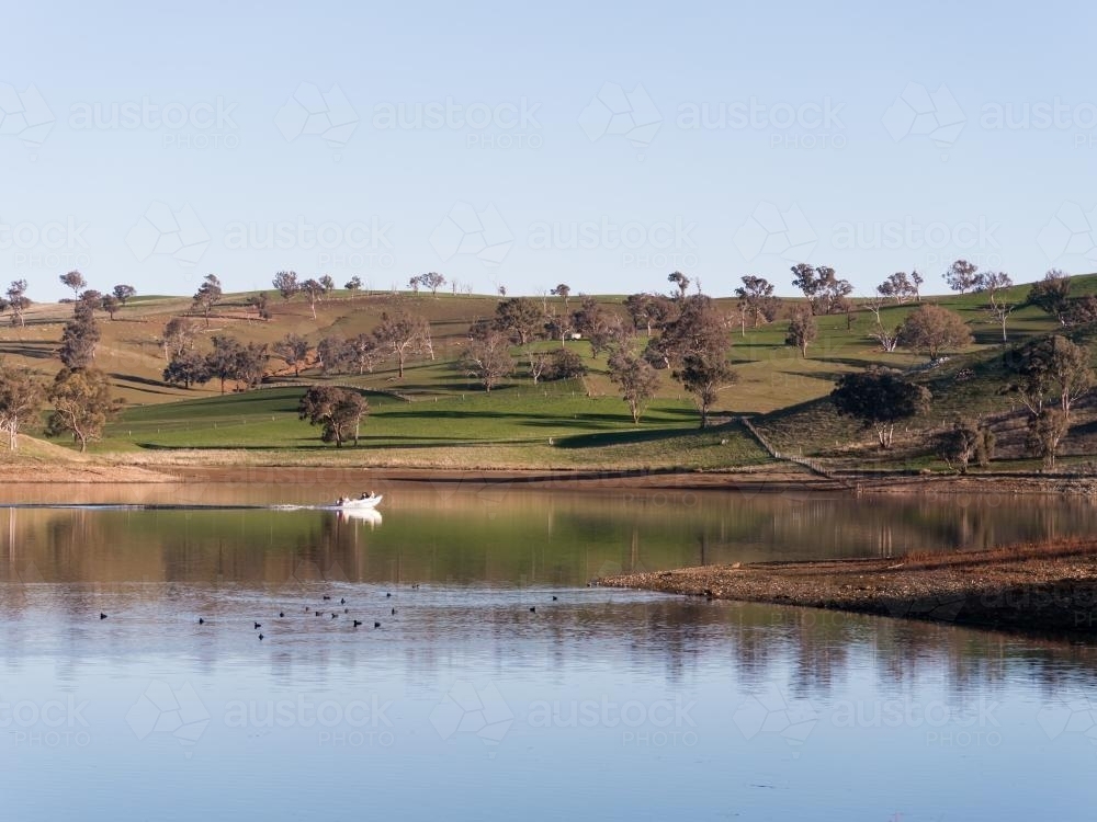Tinny travelling across a calm rural dam - Australian Stock Image