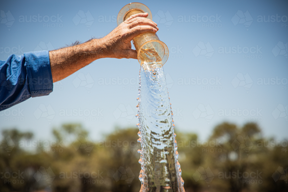 Tipping water out of a rain gauge - Australian Stock Image