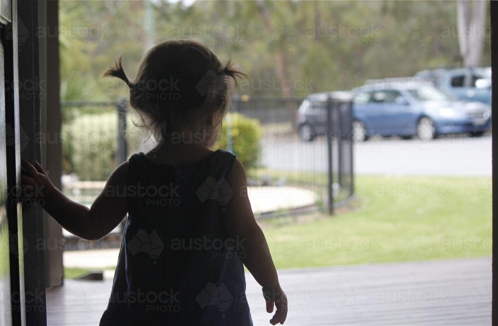 Toddler at walking out the front door of a house - Australian Stock Image