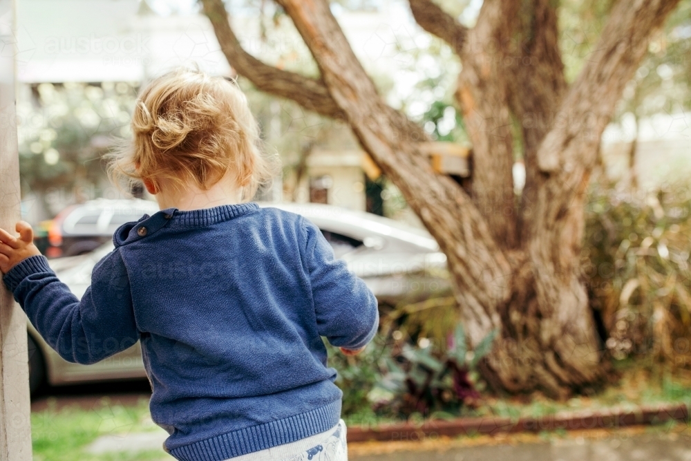 Toddler boy climbing down a step onto footpath from behind - Australian Stock Image
