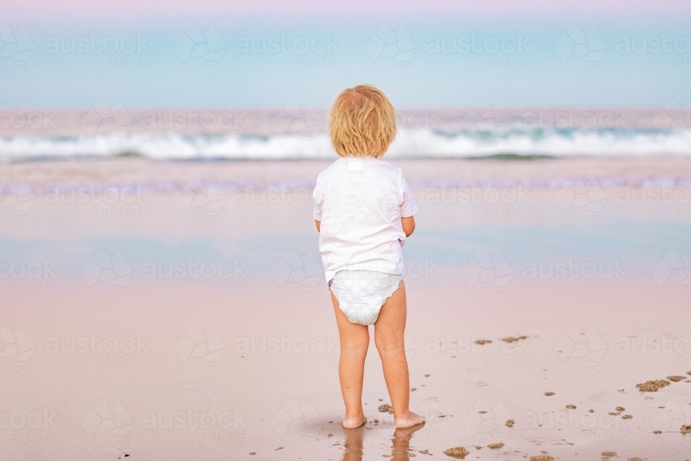Toddler boy playing on the beach at sunset while on vacation on the Gold Coast in Queensland - Australian Stock Image