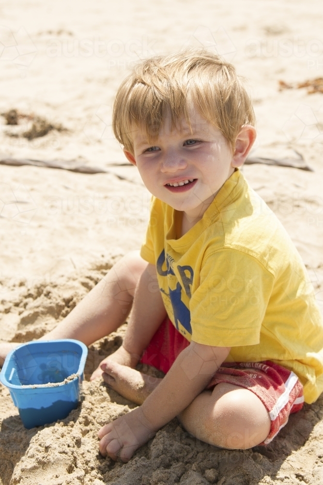 Toddler boy playing with sand at the beach - Australian Stock Image