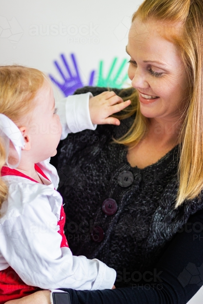 Toddler child pointing to adults mouth - Australian Stock Image