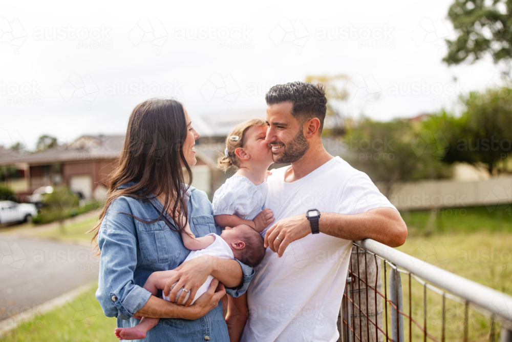 Toddler daughter kissing father on the cheek - Australian Stock Image