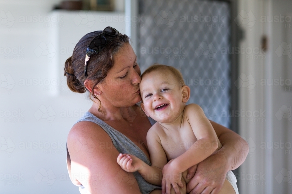 Toddler giggling in mother's arms - Australian Stock Image