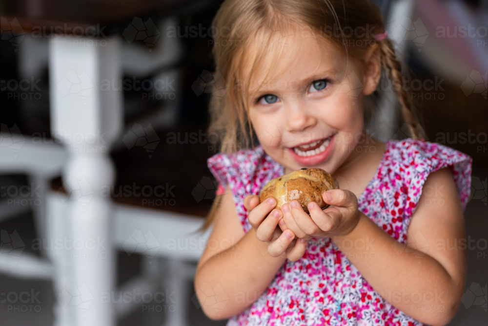 Toddler girl holding homemade hot cross bun for easter celebration - Australian Stock Image