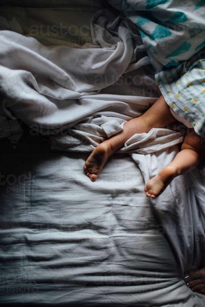 Toddler girl playing on bed - Australian Stock Image