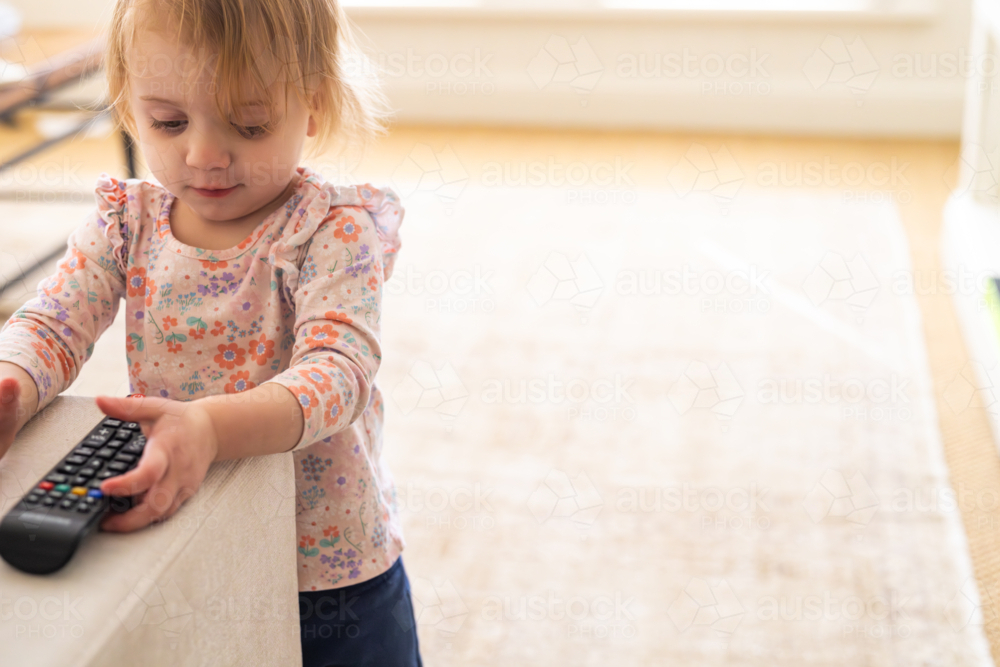 Image of Toddler girl playing with remote control in the living room ...