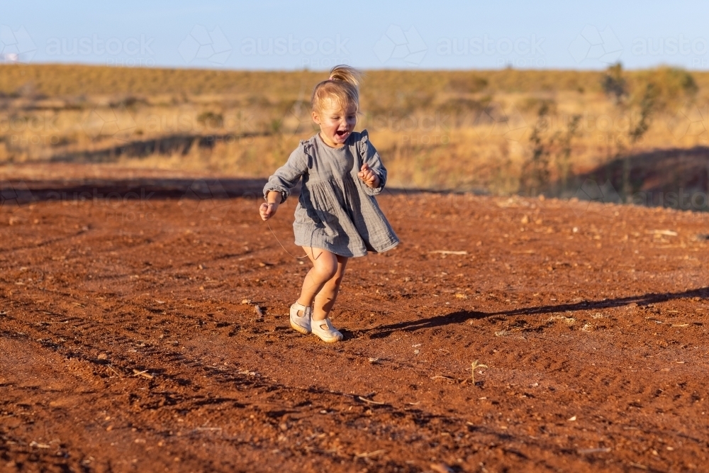 toddler girl running outdoors in the Pilbara - Australian Stock Image