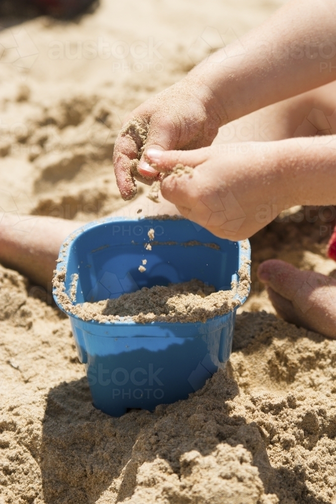 Toddler hands playing with sand at the beach - Australian Stock Image