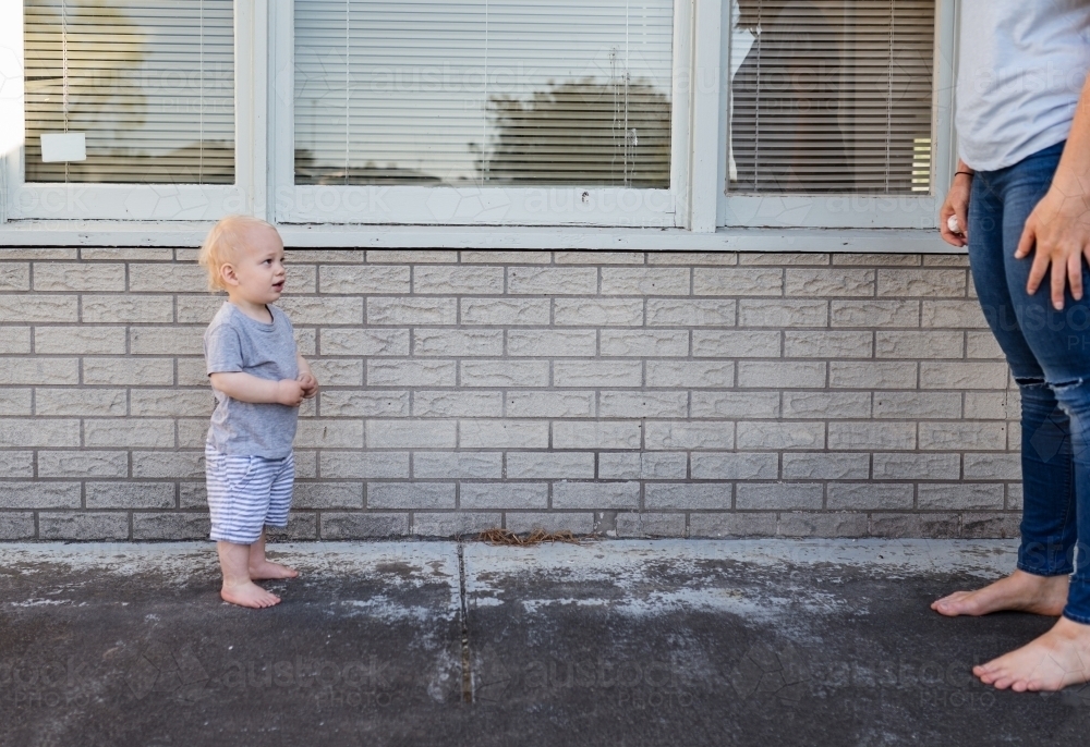 Toddler in a stand off with mum outside home - Australian Stock Image