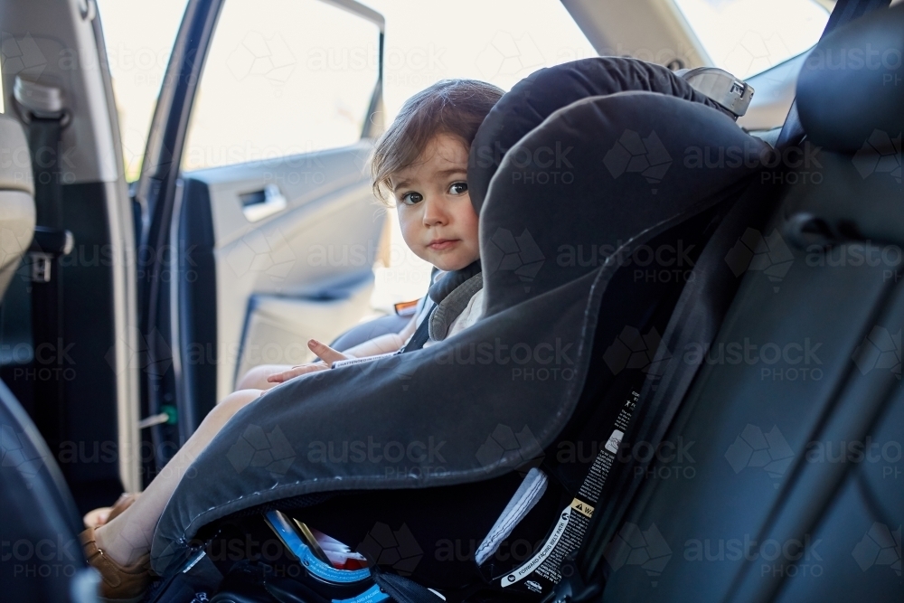 Toddler in child car seat staring at camera - Australian Stock Image