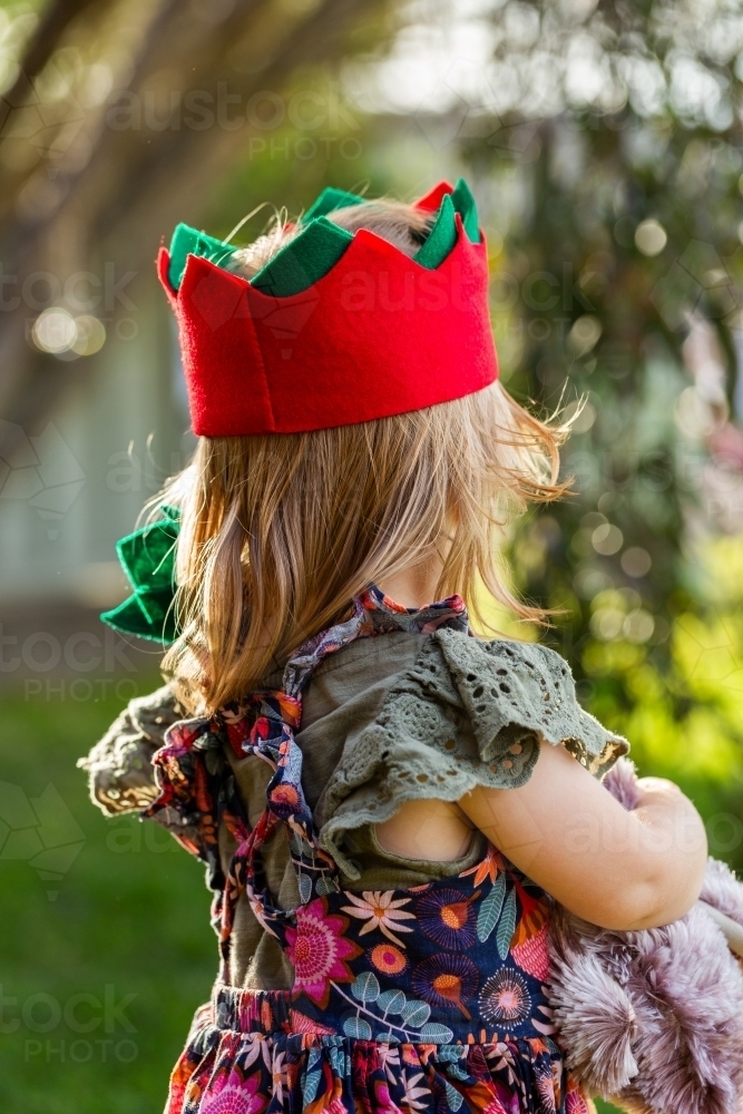 Toddler in Christmas cracker hat holding soft emu toy - Australian Stock Image