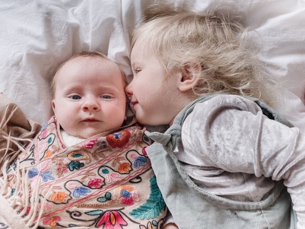 toddler kisses her baby sister. - Australian Stock Image