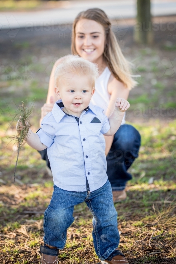 Toddler learning to walk with mum watching - Australian Stock Image