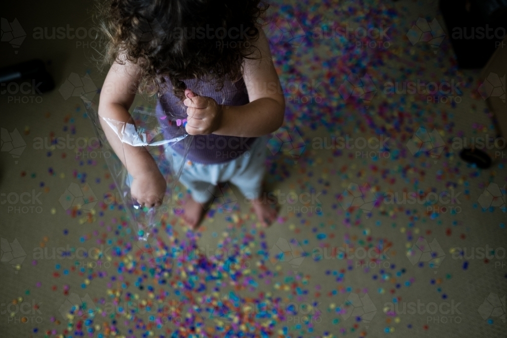 Toddler making mess with confetti - Australian Stock Image