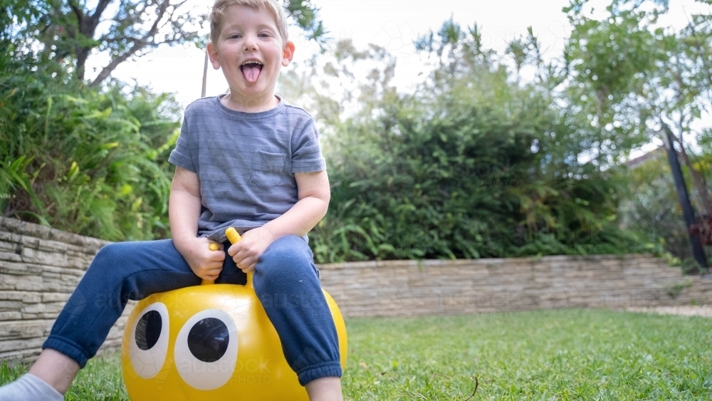 Toddler on jumping ball in backyard - Australian Stock Image
