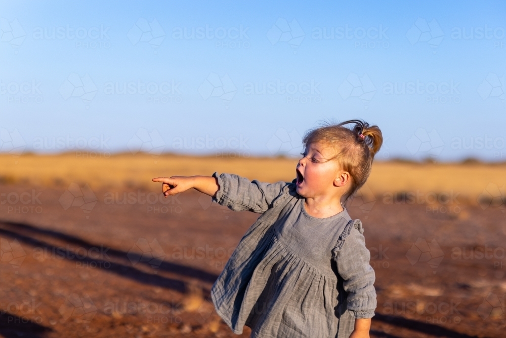 toddler outdoors excitedly pointing into distance - Australian Stock Image