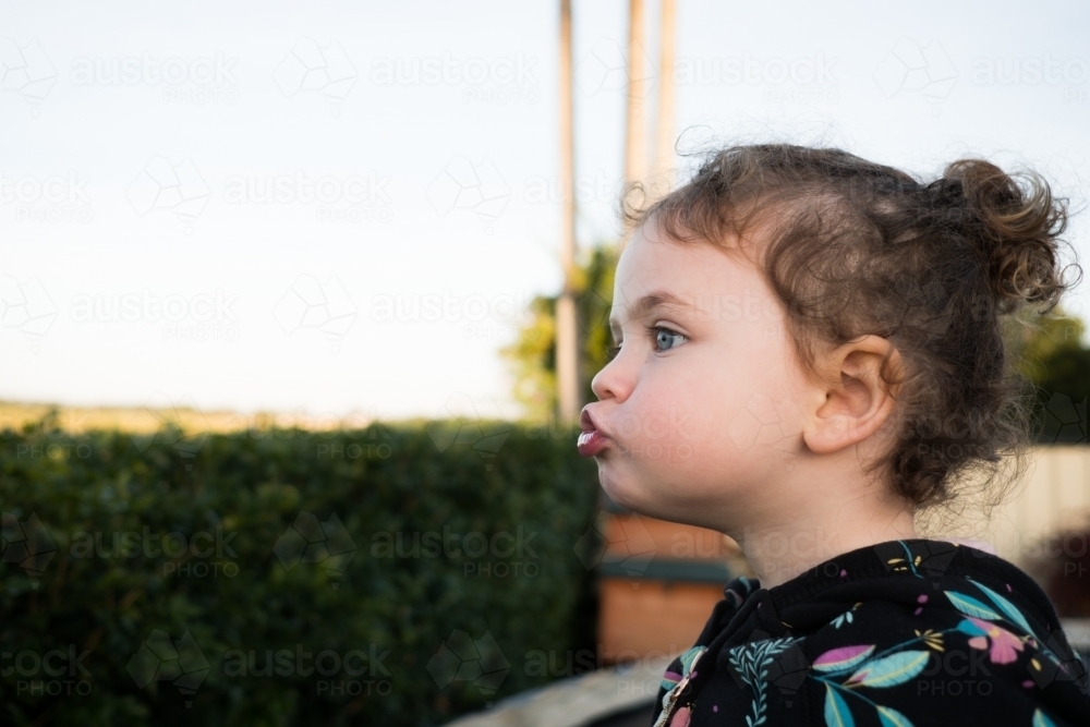 Toddler pulling a silly face outdoors - Australian Stock Image