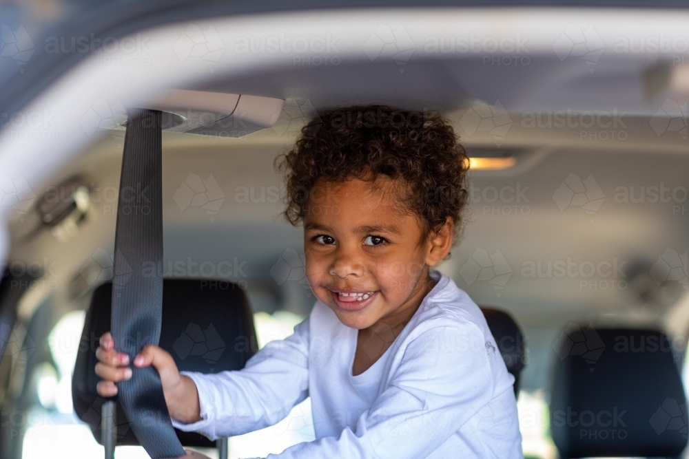 toddler pulling on seatbelt strap in a car - Australian Stock Image