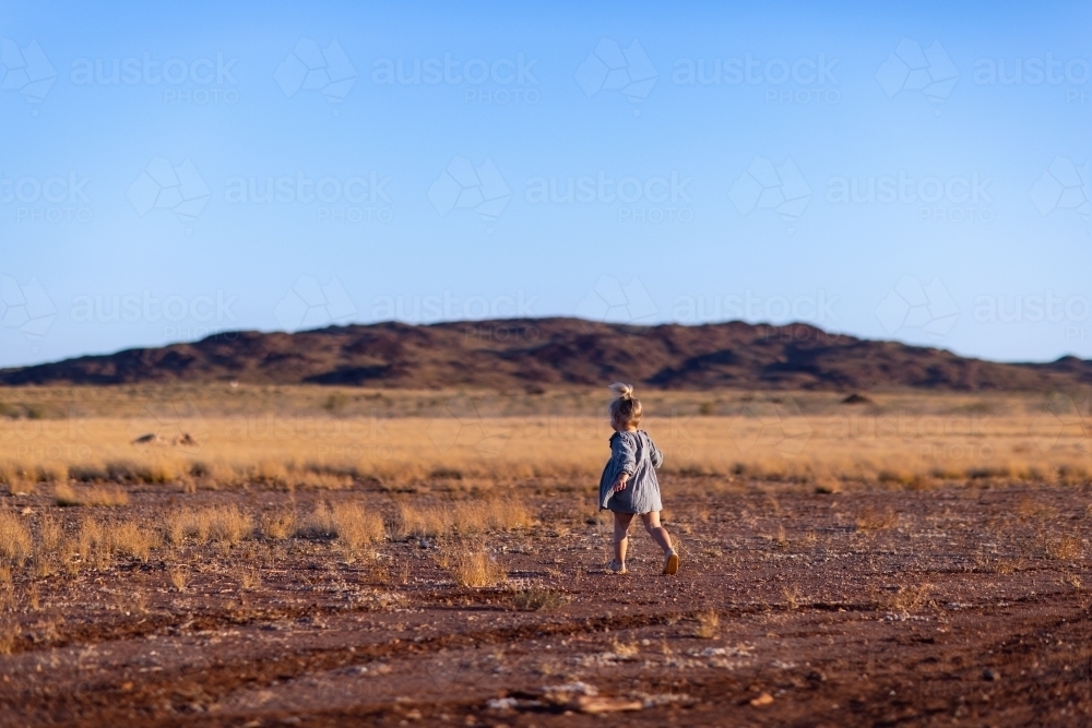toddler running away in outback landscape - Australian Stock Image