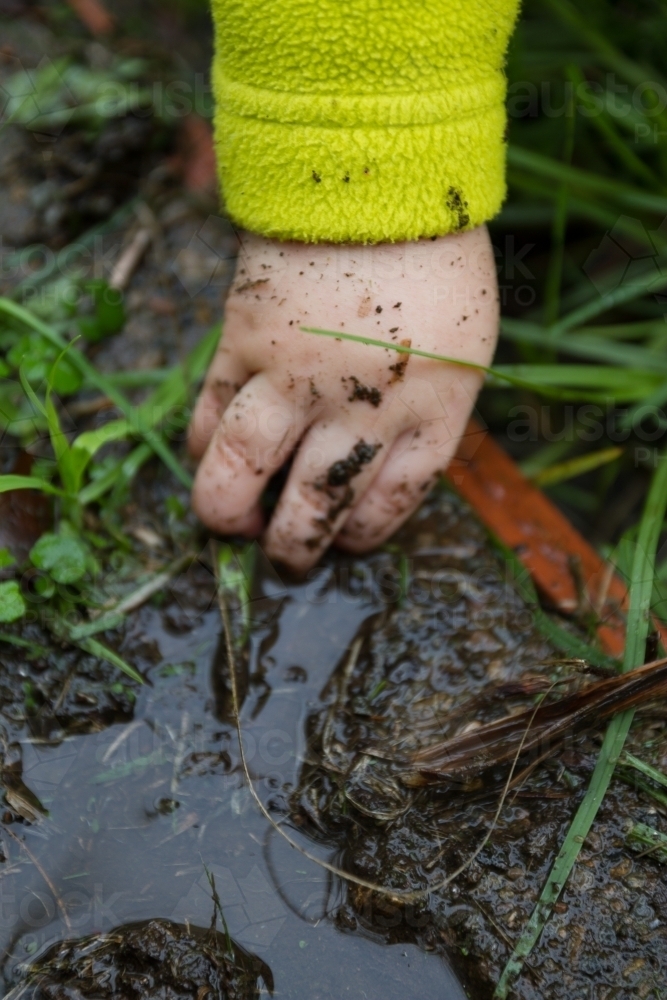 Toddler's hand in the wet mud - Australian Stock Image
