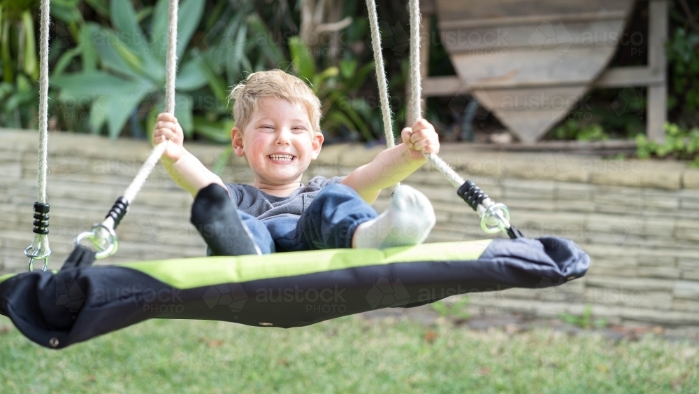 Toddler smiling on swing - Australian Stock Image