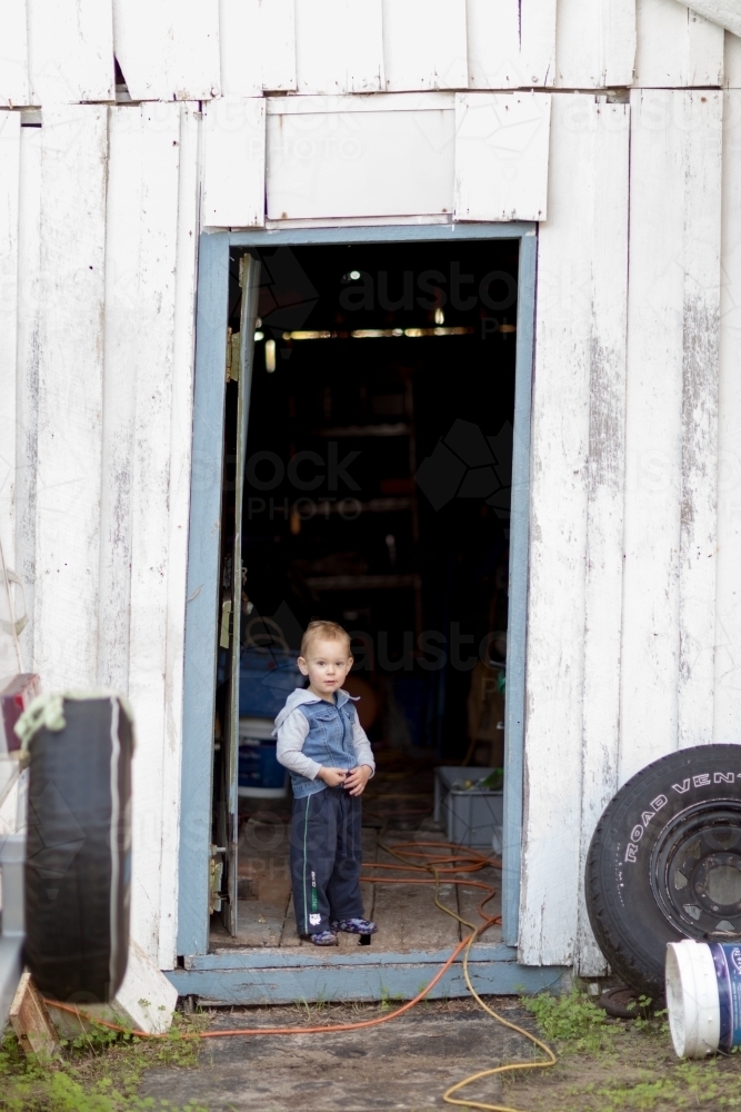 Toddler standing in doorway of shed - Australian Stock Image
