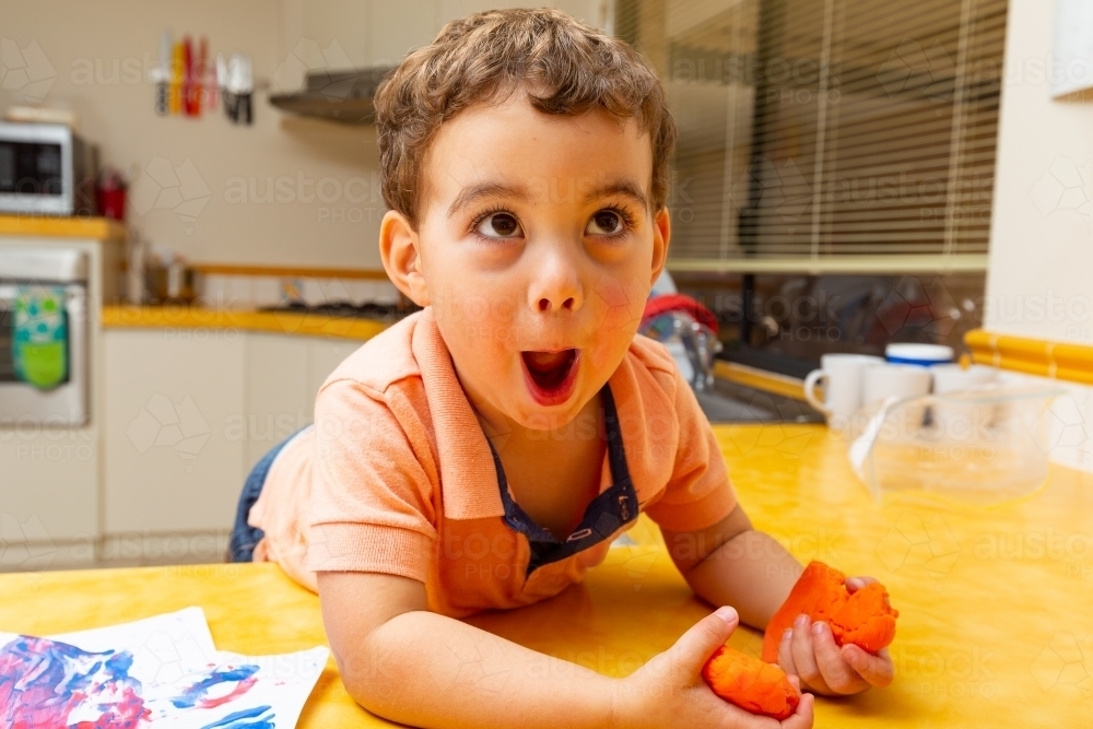 toddler with funny face playing in the kitchen - Australian Stock Image