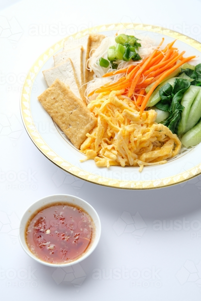 Tofu and egg noodle salad served in a bowl with a gold rim. - Australian Stock Image