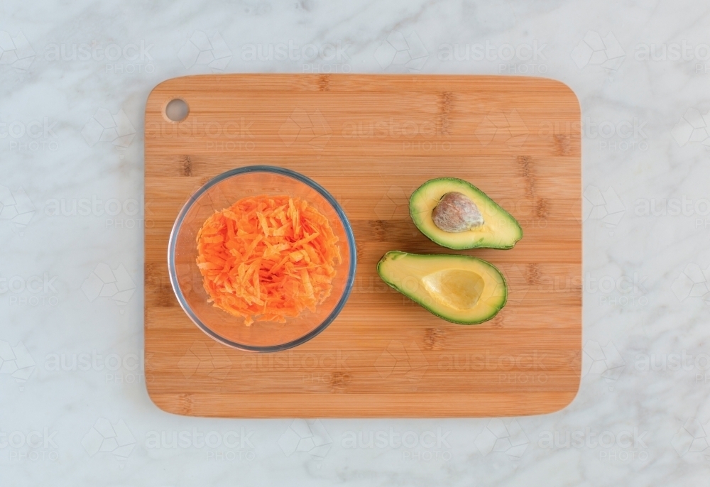 Top down of carrot and avocado ingredients on chopping block - Australian Stock Image