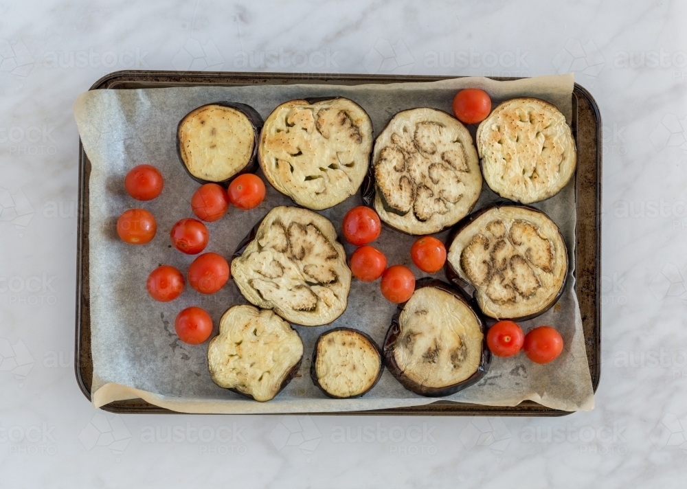 Top down of cherry tomatoes and eggplant on baking tray - Australian Stock Image