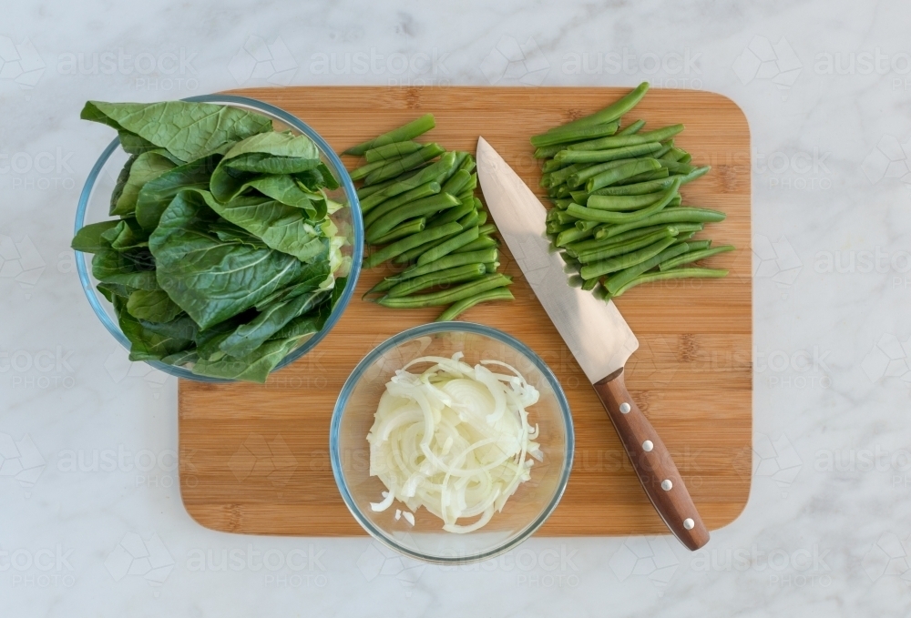 Top down of green vegetable ingredients with knife on chopping board - Australian Stock Image