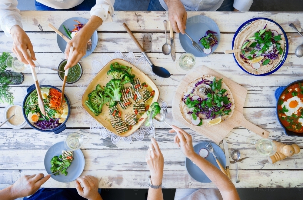 Top down of people eating a meal at rustic table - Australian Stock Image