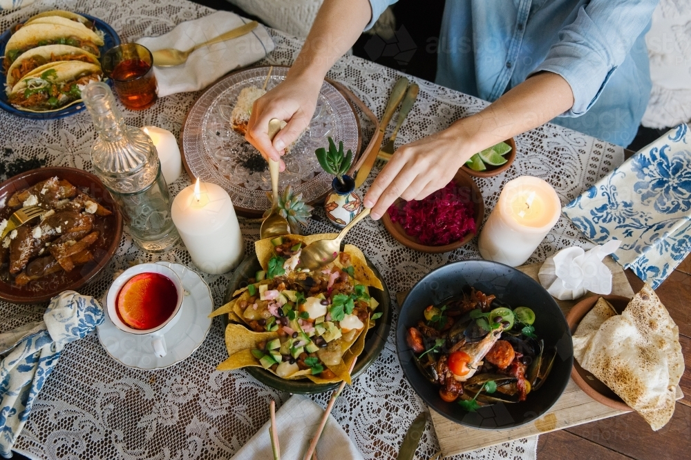 Top-down view of a table with various dishes and people eating. - Australian Stock Image