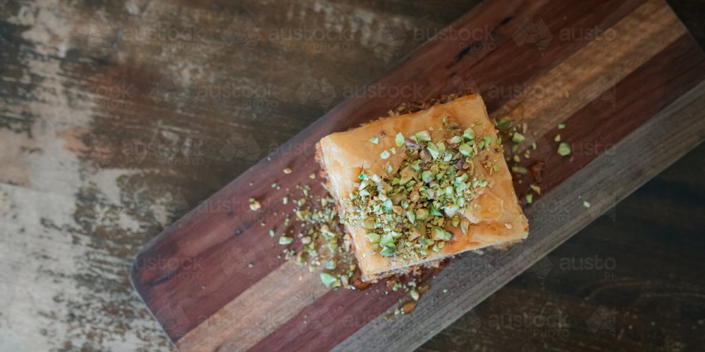 Top down view of Baklava on wooden board with chopped pistachios. Banner with copy space. - Australian Stock Image