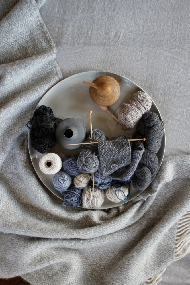 Top down view of knitting, wool and vases on grey blanket and linen - Australian Stock Image