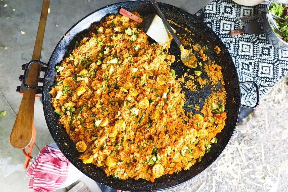 Top down view of paella cooking in a large pan - Australian Stock Image