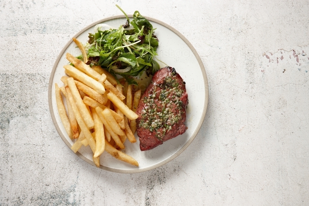Top down view of steak with salsa verde, chips and green salad - Australian Stock Image
