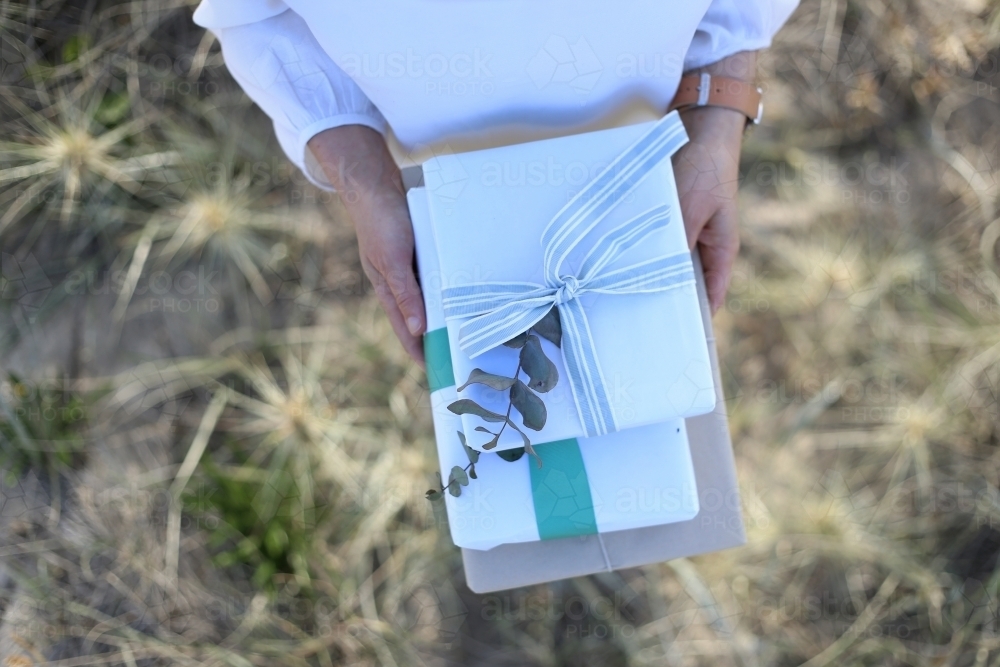 Top down woman holding presents with sea grass in background - Australian Stock Image
