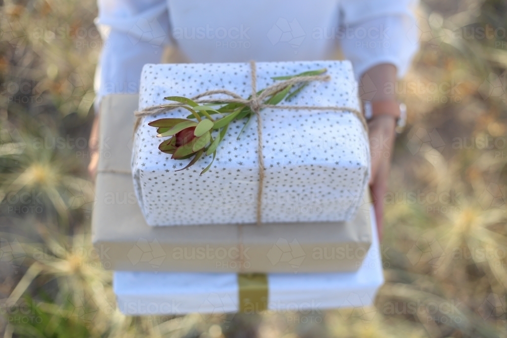 Top down woman holding presents with sea grass in background - Australian Stock Image