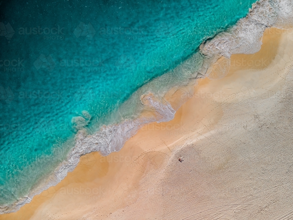 top shot of a beach with a white sand shore and sea waves on a sunny day - Australian Stock Image