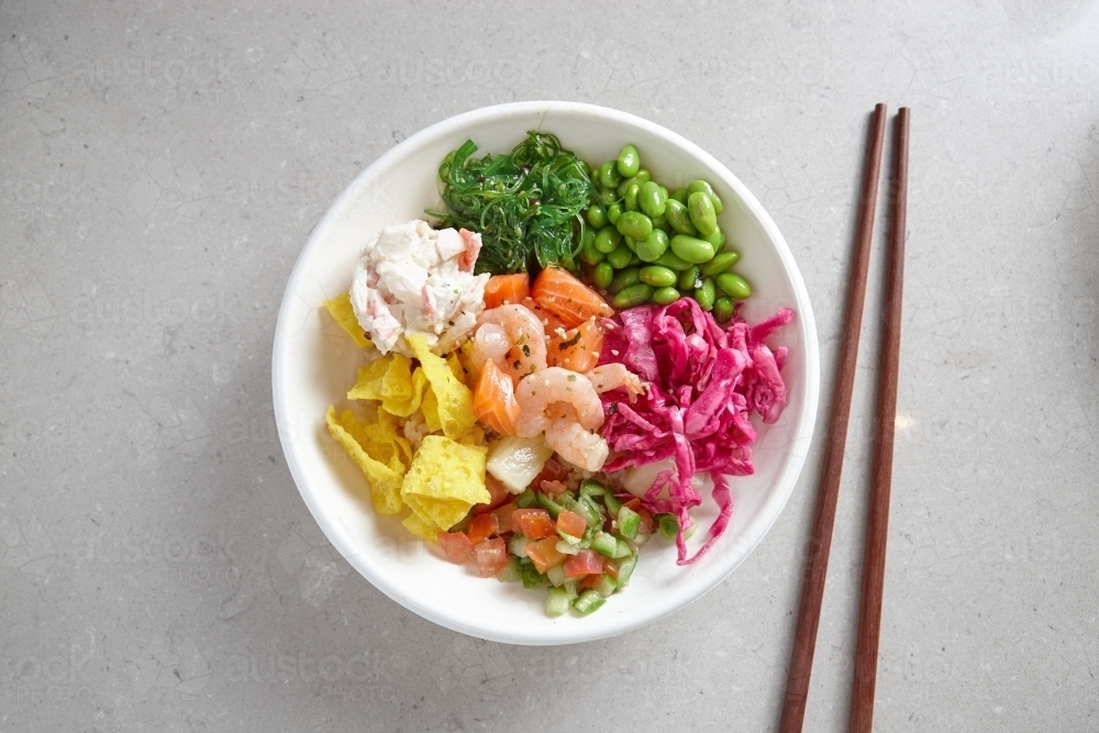 top shot of a bowl of  seafood salad with wooden chopsticks on grey background - Australian Stock Image