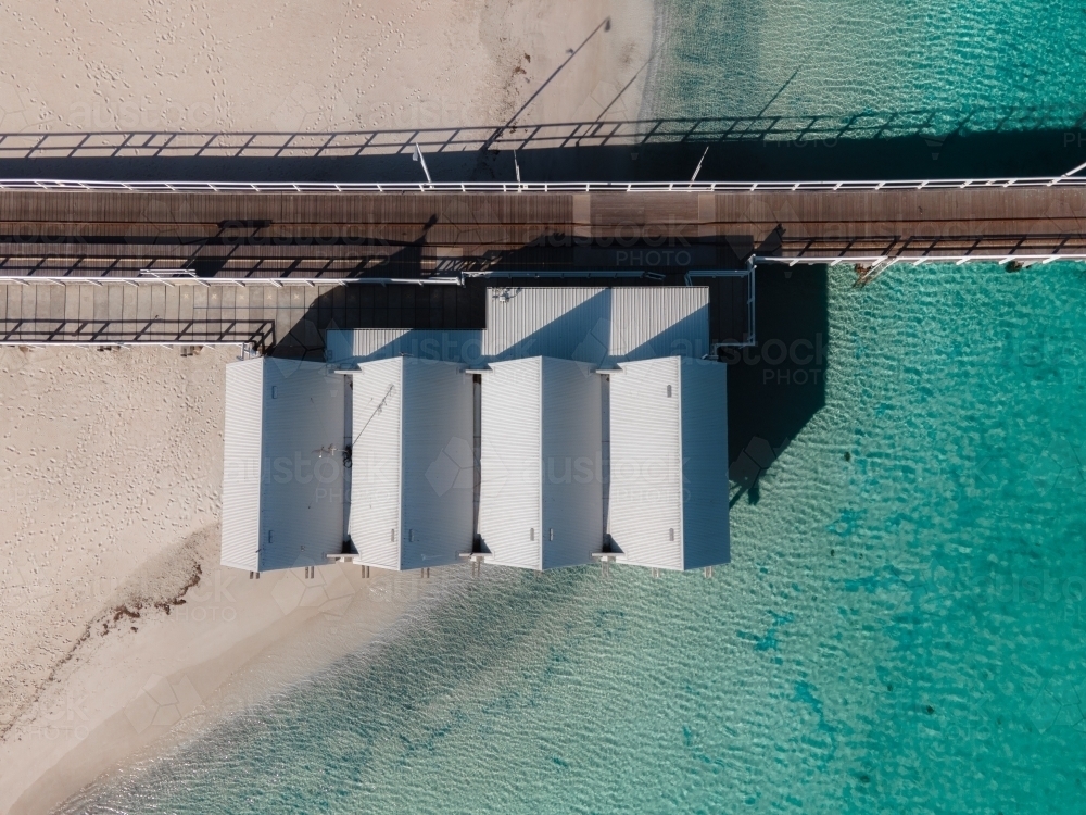 top shot of four beach houses with walkway with clear waters and white sand - Australian Stock Image