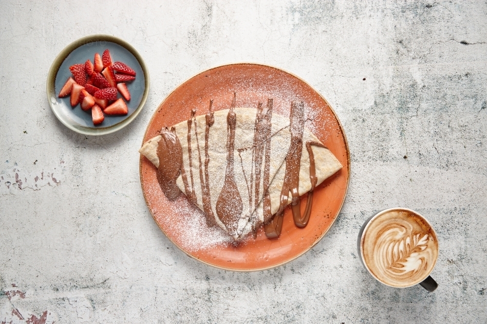 Top view down of crepe with chocolate sauce  with strawberries and cup of coffee on the side - Australian Stock Image