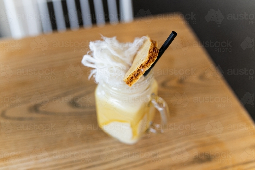 Top view of coffee with caramel on the sides with fairy floss, biscuit and a straw on top - Australian Stock Image