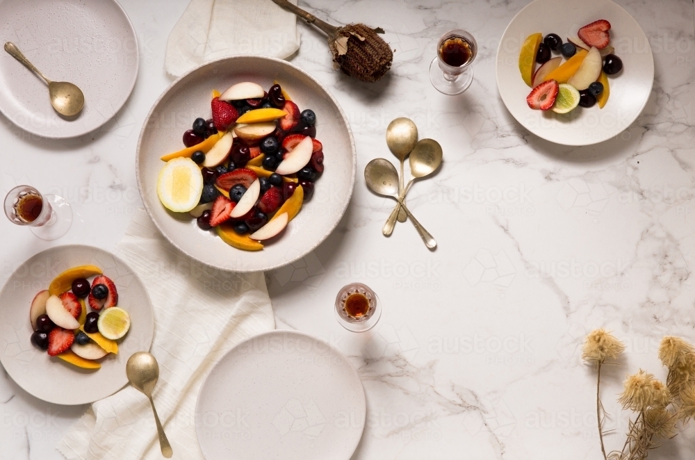 Top view of mixed stone fruit salad brunch with guests on light background - Australian Stock Image